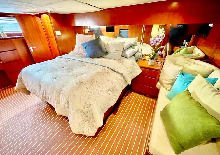 New Beginning Yacht Photos Pics Luxurious bedroom interior of a 1990 Cheoy Lee 75 yacht with cozy bedding and elegant decor.