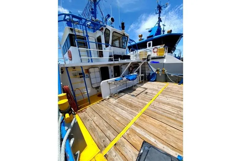 Yacht Photos Pics Custom 2008 boat with wooden deck and blue accents, docked under clear sky.