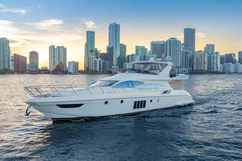 Drakkar Yacht Photos Pics Luxurious 2012 Azimut Evolution yacht cruising near a city skyline at sunset.