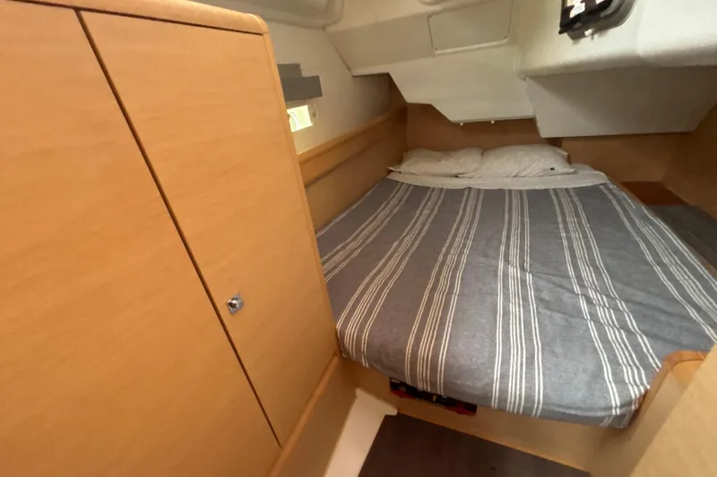 Statira Yacht Photos Pics 2017 Jeanneau Sun Odyssey 389 cabin with striped bedding and wooden cabinetry.