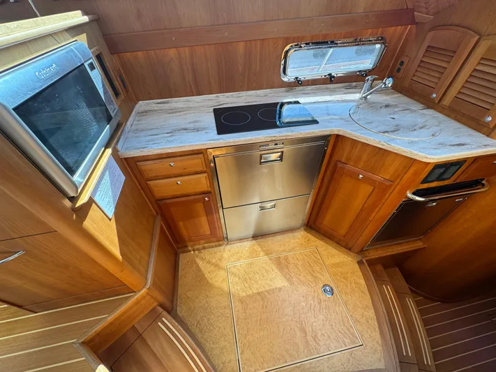  Yacht Photos Pics 2019 Sabre 42 Salon Express kitchen with wood cabinetry, stove, and stainless steel appliances.