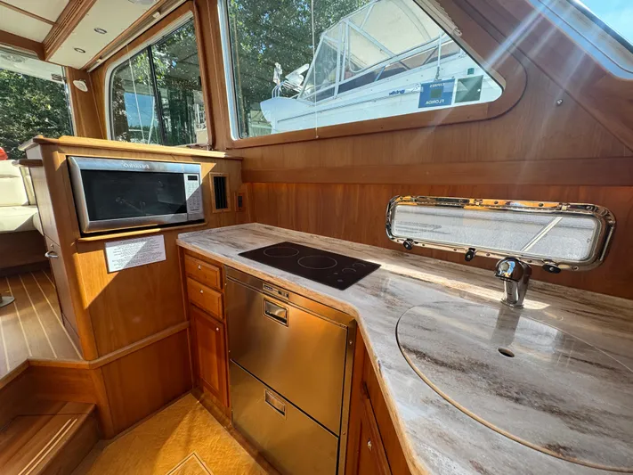  Yacht Photos Pics 2019 Sabre 42 Salon Express yacht interior with modern kitchen, featuring wood cabinetry and stainless appliances.