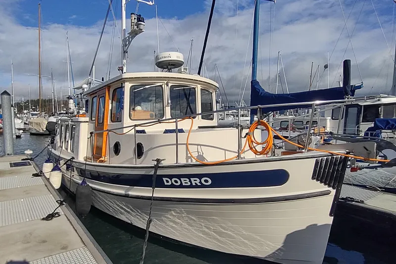 Dobro Yacht Photos Pics 1990 Nordic Tug 32 docked at marina under cloudy sky.