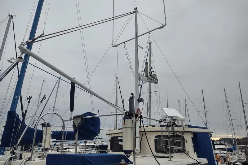 Dobro Yacht Photos Pics 1990 Nordic Tug 32 in marina, surrounded by sailboats under cloudy sky.