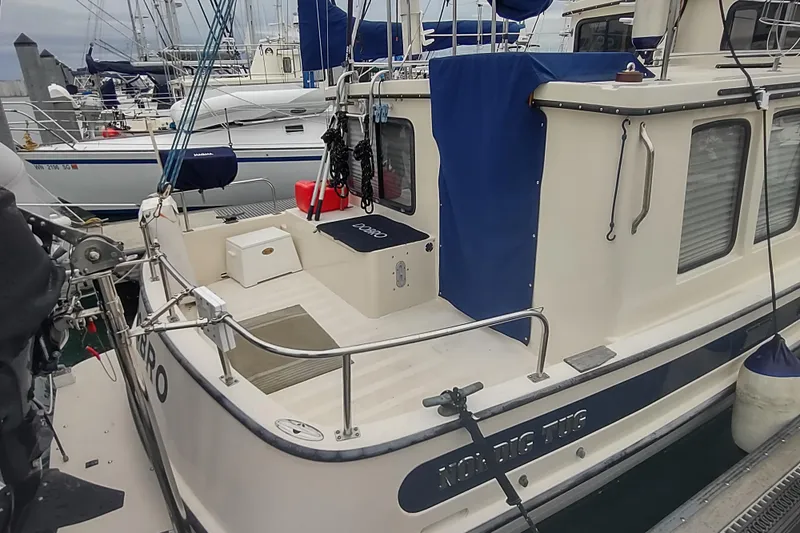 Dobro Yacht Photos Pics 1990 Nordic Tug 32 docked, featuring a spacious deck and nautical equipment.