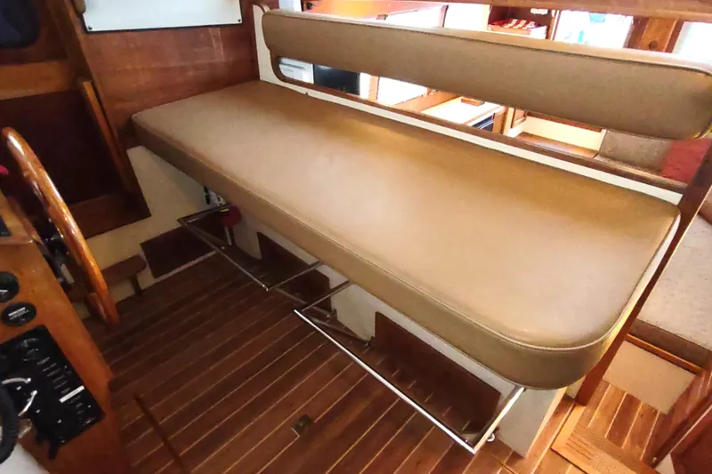 Dobro Yacht Photos Pics 1990 Nordic Tug 32 interior with cushioned seating and wooden flooring.