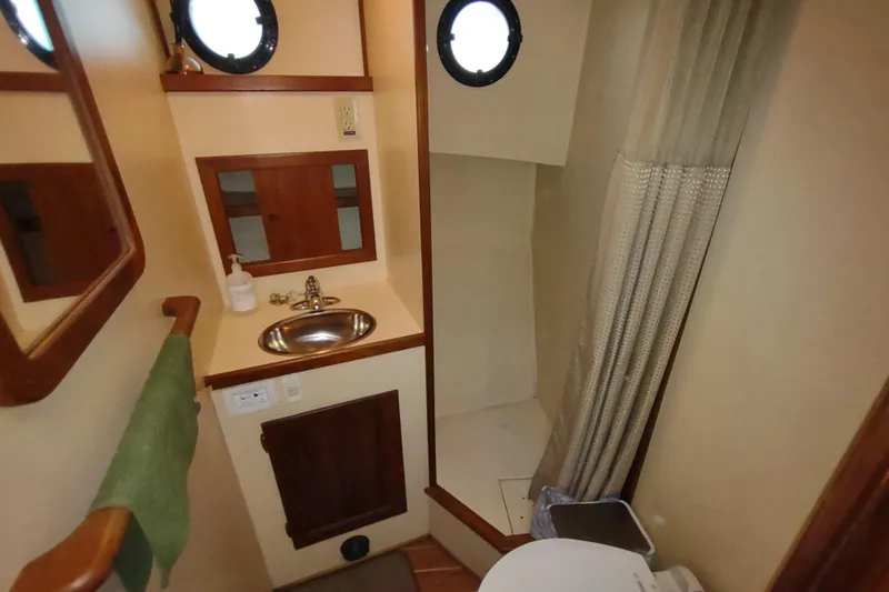 Dobro Yacht Photos Pics Bathroom interior of a 1990 Nordic Tug 32, featuring sink, mirror, and shower area.