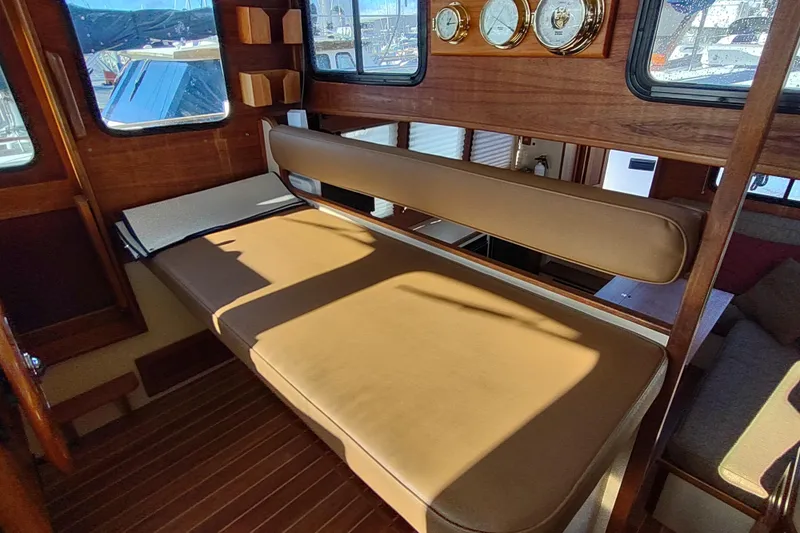 Dobro Yacht Photos Pics Interior of a 1990 Nordic Tug 32 with wooden accents and cushioned seating.