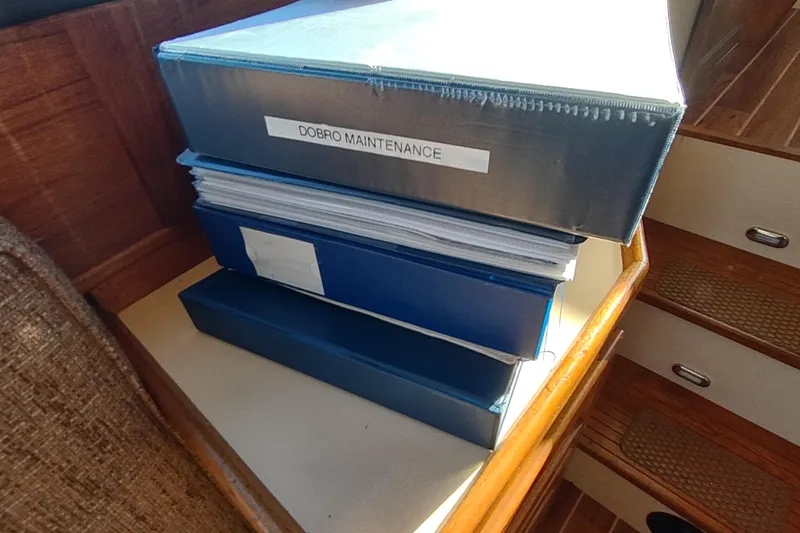 Dobro Yacht Photos Pics Binders labeled "Dobro Maintenance" on a Nordic Tug 32, 1990 model, wooden interior.