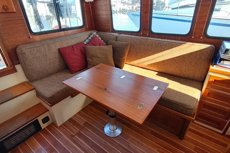 Dobro Yacht Photos Pics Cozy interior of a 1990 Nordic Tug 32 with cushioned seating and wooden table.
