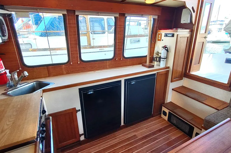 Dobro Yacht Photos Pics Interior of a 1990 Nordic Tug 32, featuring a compact kitchen with wooden accents.