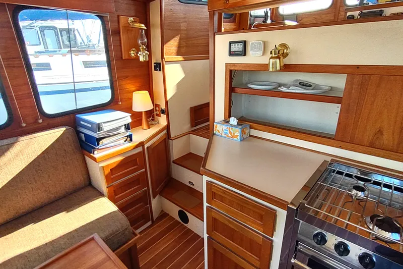 Dobro Yacht Photos Pics Cozy interior of 1990 Nordic Tug 32 with wood accents and compact kitchen.