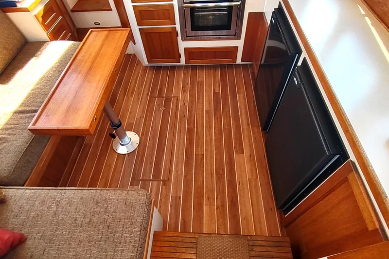 Dobro Yacht Photos Pics Interior of a 1990 Nordic Tug 32, featuring wood flooring and compact kitchen area.