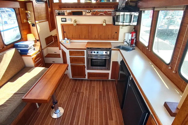Dobro Yacht Photos Pics Interior of 1990 Nordic Tug 32 with wood finish, kitchen, and seating area.