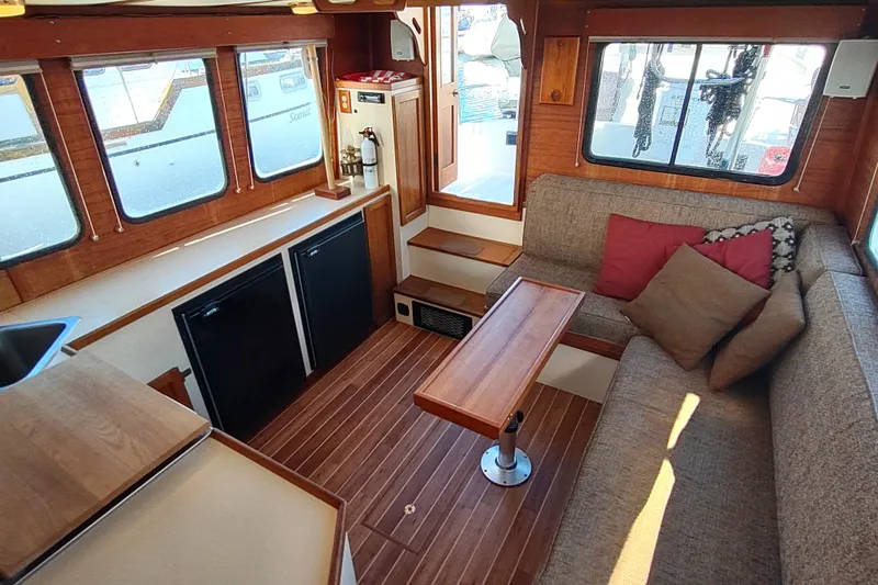 Dobro Yacht Photos Pics Interior of a 1990 Nordic Tug 32, featuring cozy seating and wooden accents.