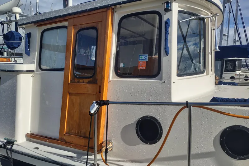 Dobro Yacht Photos Pics 1990 Nordic Tug 32 boat with wooden door and portholes, docked at marina.