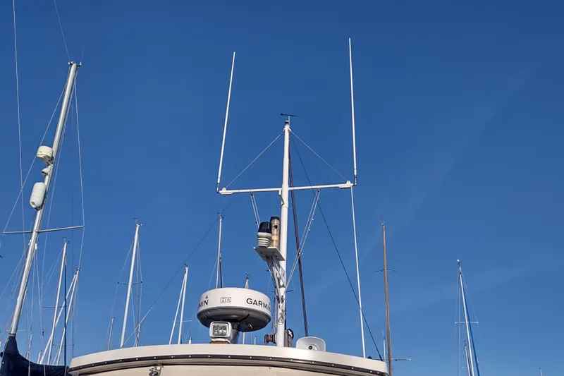 Dobro Yacht Photos Pics Nordic Tug 32 (1990) with radar and antennas against clear blue sky.
