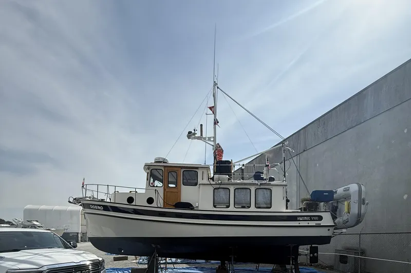 Dobro Yacht Photos Pics 1990 Nordic Tug 32 boat on dry dock, side view, under clear sky.