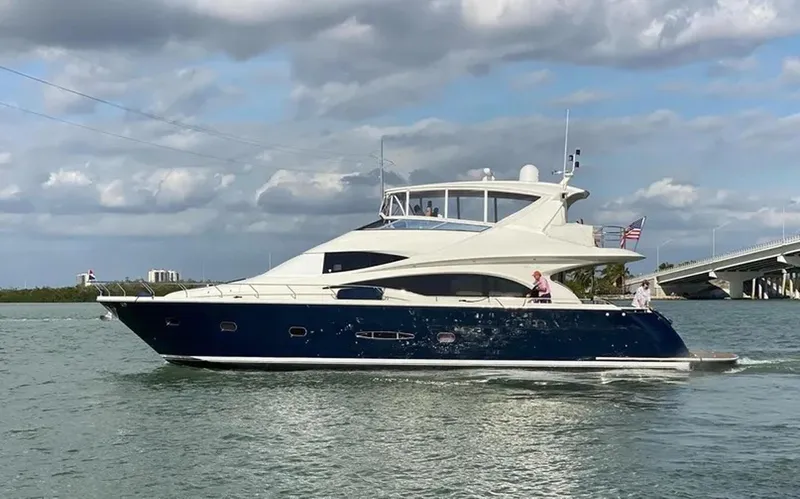 Bad Bettye Yacht Photos Pics Luxury 2006 Marquis 65 yacht cruising on a sunny day, with American flag.