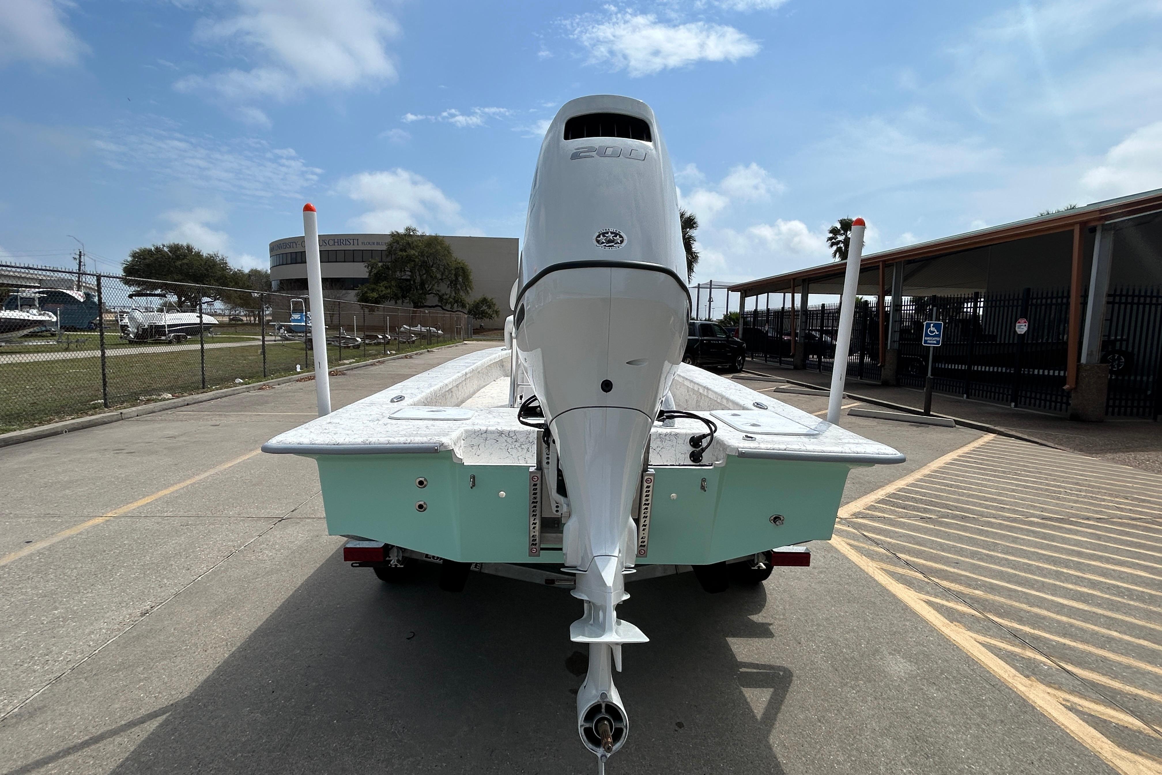2026 Coastal Skiff 231 Flats boat with powerful outboard motor, parked on a sunny day.