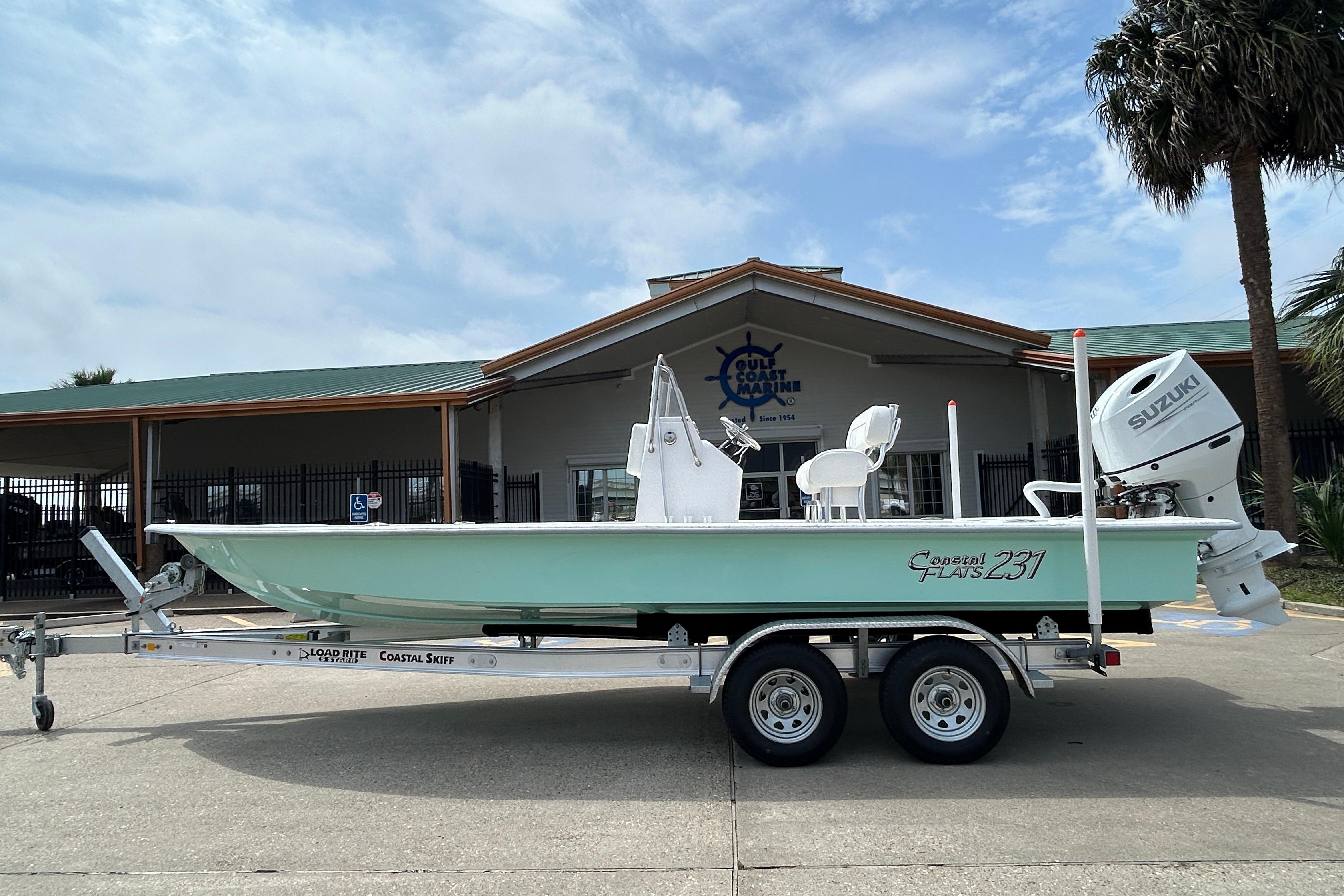 2026 Coastal Skiff 231 Flats boat on trailer, parked outside a marine store.