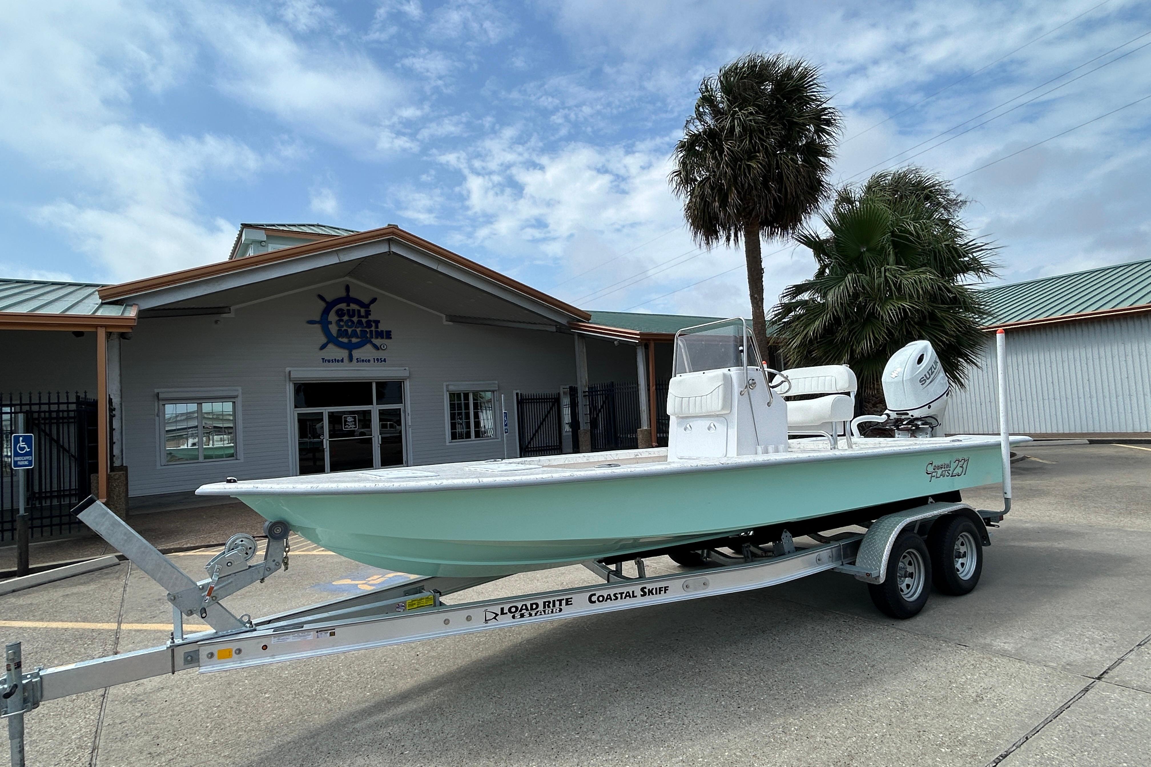 2026 Coastal Skiff 231 Flats boat on trailer outside maritime building.