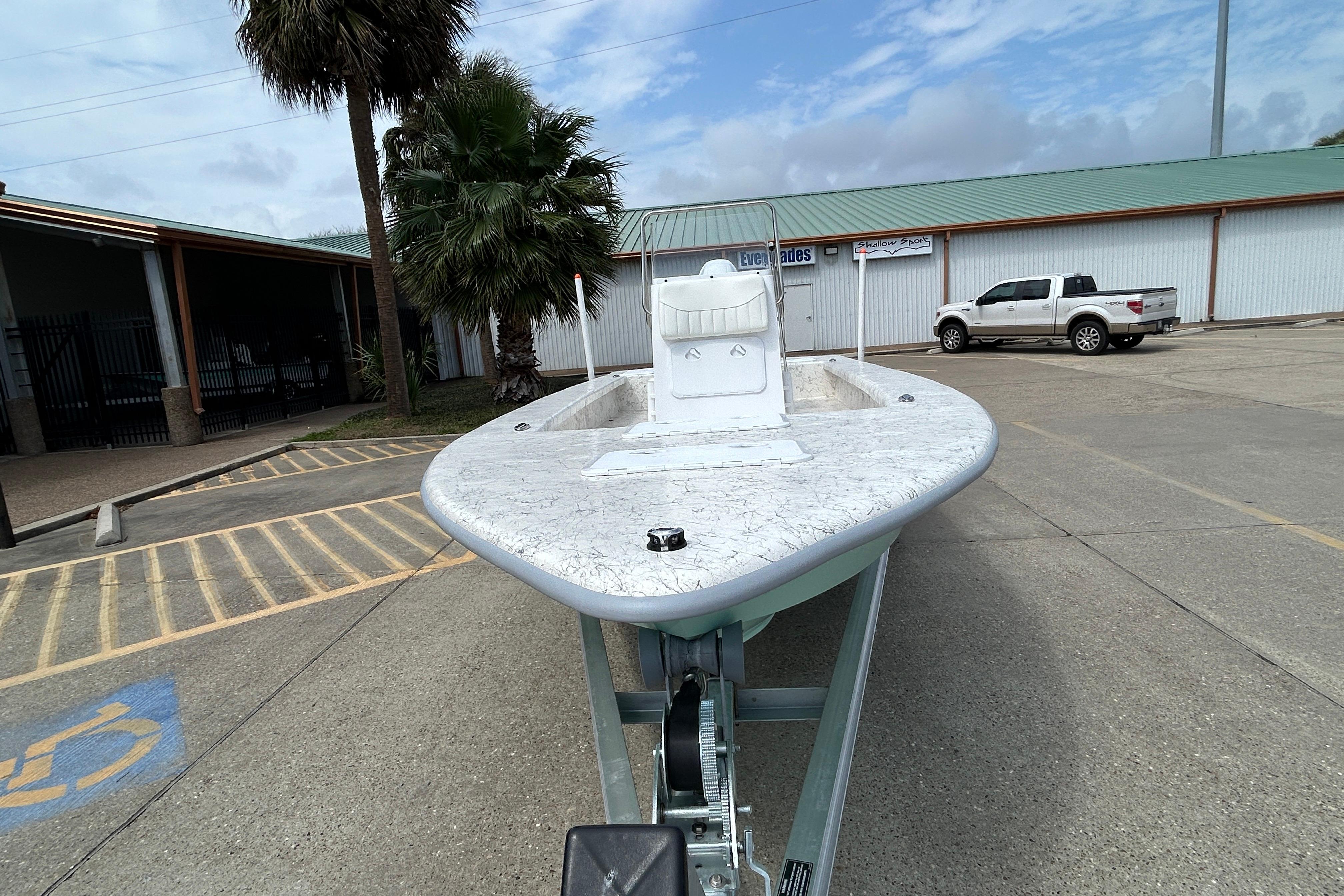 2026 Coastal Skiff 231 Flats boat on trailer in parking lot, palm tree nearby.