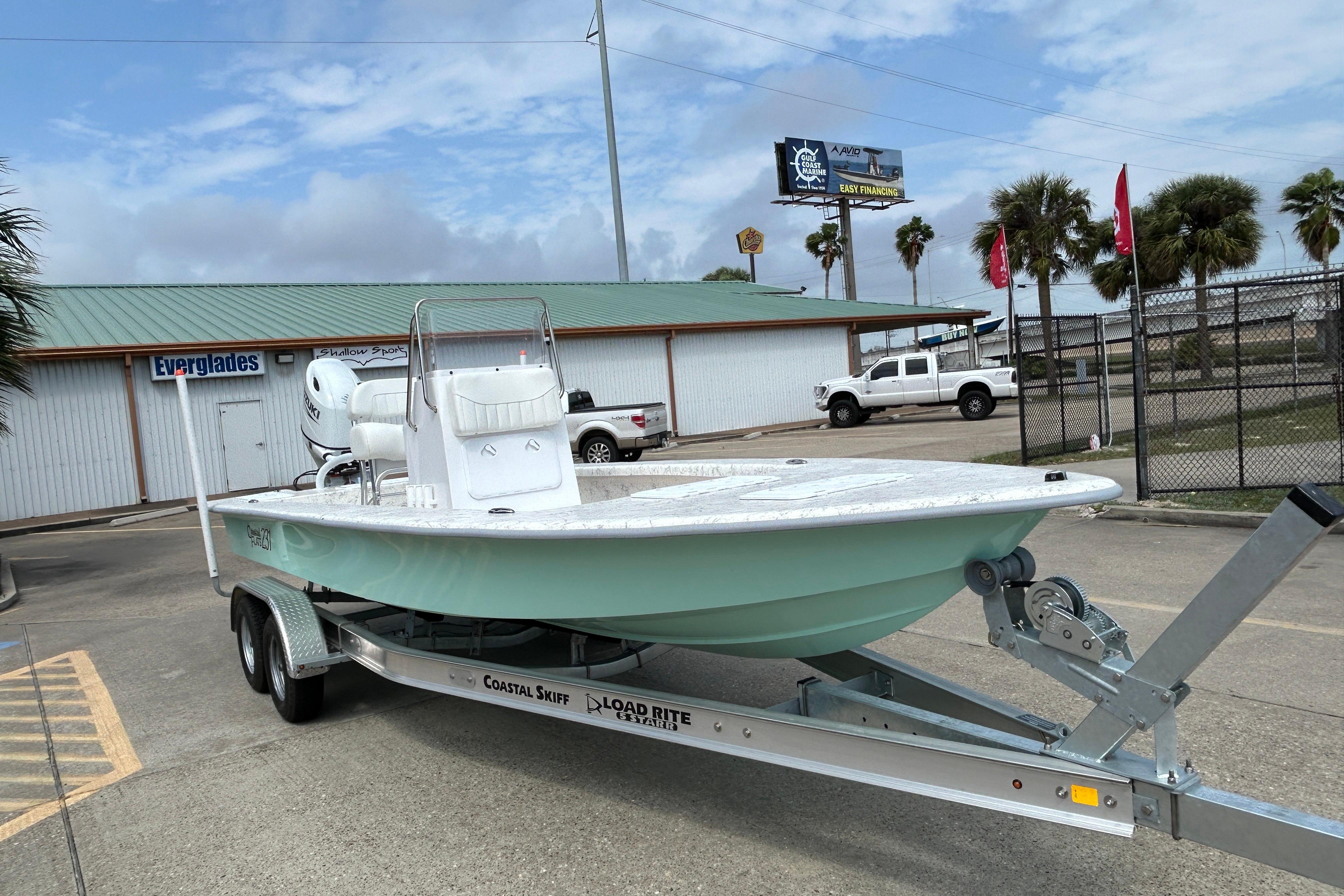2026 Coastal Skiff 231 Flats boat on trailer, parked outdoors near dealership.
