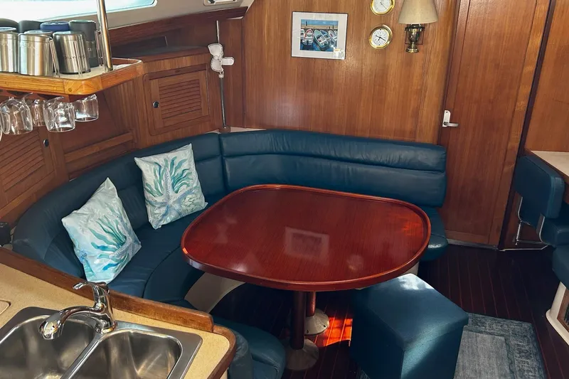 Simpatico Yacht Photos Pics Cozy interior of 1999 Catalina 42 MkII sailboat with wooden table and blue seating.