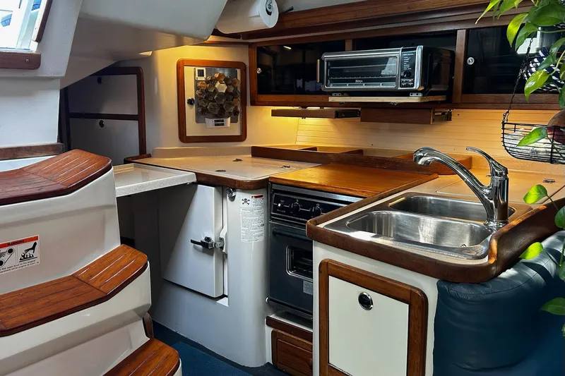 Simpatico Yacht Photos Pics Interior of a 1999 Catalina 42 MkII yacht kitchen with wooden cabinetry and modern appliances.