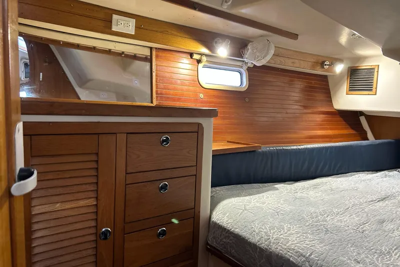 Simpatico Yacht Photos Pics Interior of a 1999 Catalina 42 MkII sailboat cabin with wooden cabinetry and cozy bedding.
