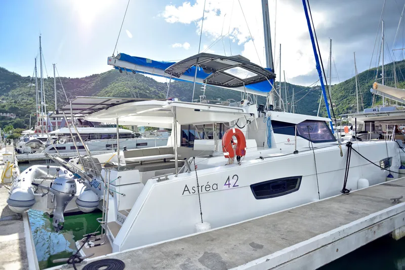 Boomerang Yacht Photos Pics 2022 Fountaine Pajot Astrea 42 catamaran docked at marina with scenic mountain backdrop.