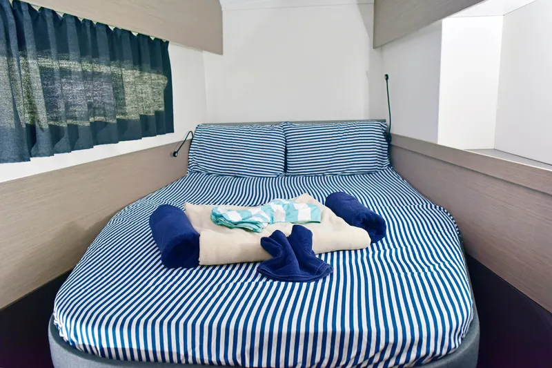 Boomerang Yacht Photos Pics Cozy cabin interior of 2022 Fountaine Pajot Astrea 42 with striped bedding and folded towels.