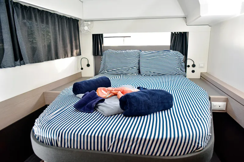 Boomerang Yacht Photos Pics Luxurious cabin interior of 2022 Fountaine Pajot Astrea 42 with striped bedding and towels.