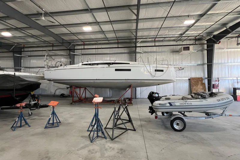 Job Site Yacht Photos Pics 2023 Jeanneau Sun Odyssey 380 sailboat in indoor storage, alongside a small inflatable boat.