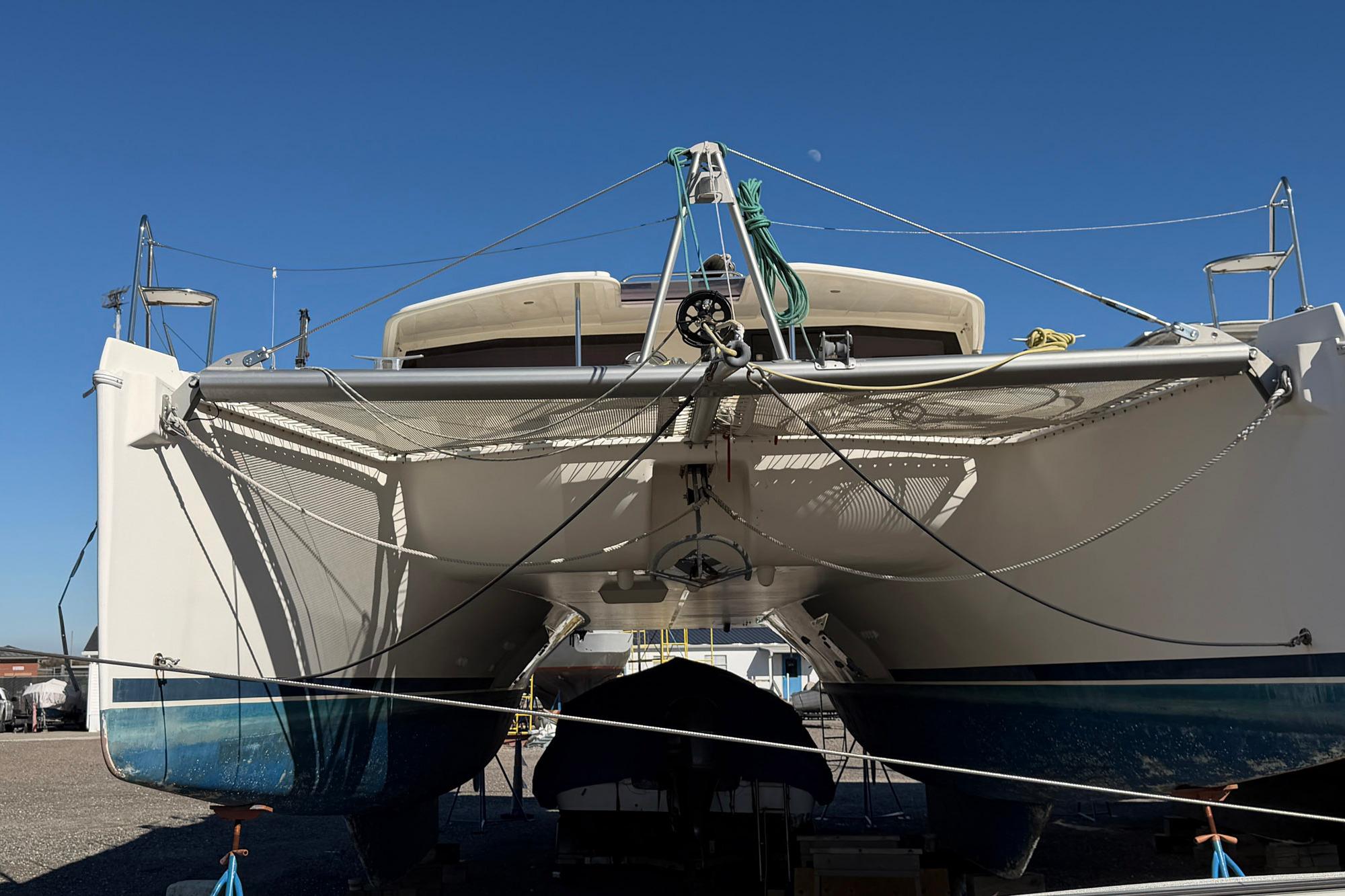 2015 Leopard 48 catamaran on land, showcasing hull and netting under clear blue sky.