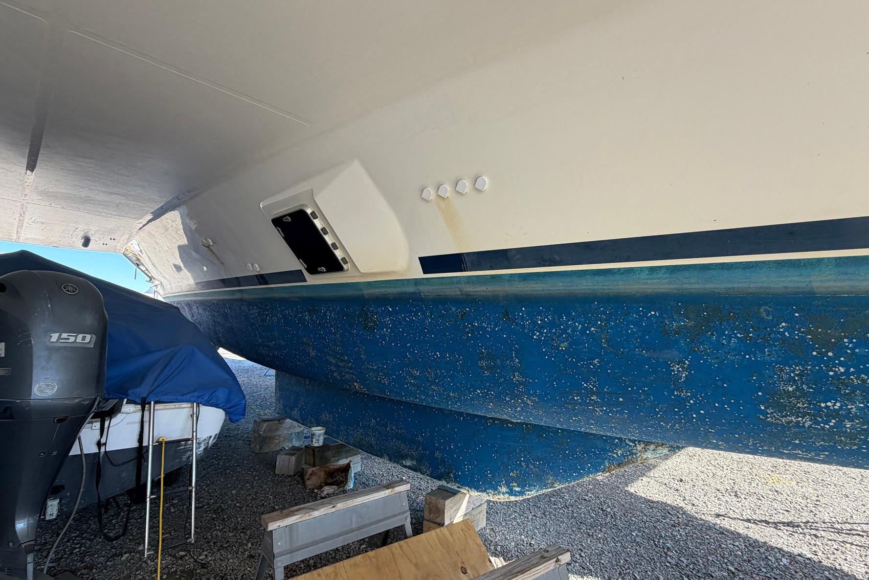 Underneath view of a 2015 Leopard 48 yacht on dry dock, showing hull and outboard motor.