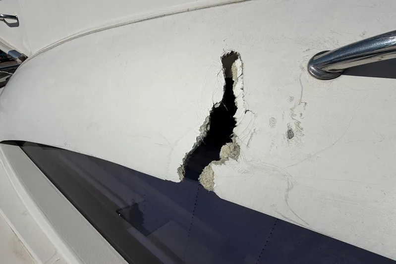 Gratitude Yacht Photos Pics Damaged hull of 2015 Leopard 48 yacht with visible hole and fiberglass exposure.