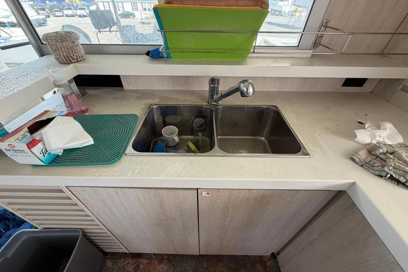 Gratitude Yacht Photos Pics Kitchen sink area in a 2015 Leopard 48 yacht with dishes and cleaning supplies.