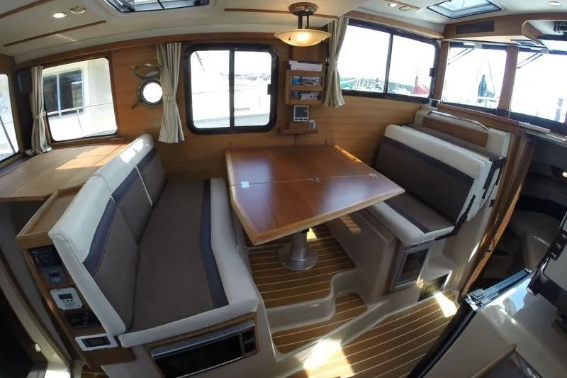 Mi Callao Yacht Photos Pics Interior of 2015 Ranger Tugs R-31S, featuring cozy seating and wooden dining table.