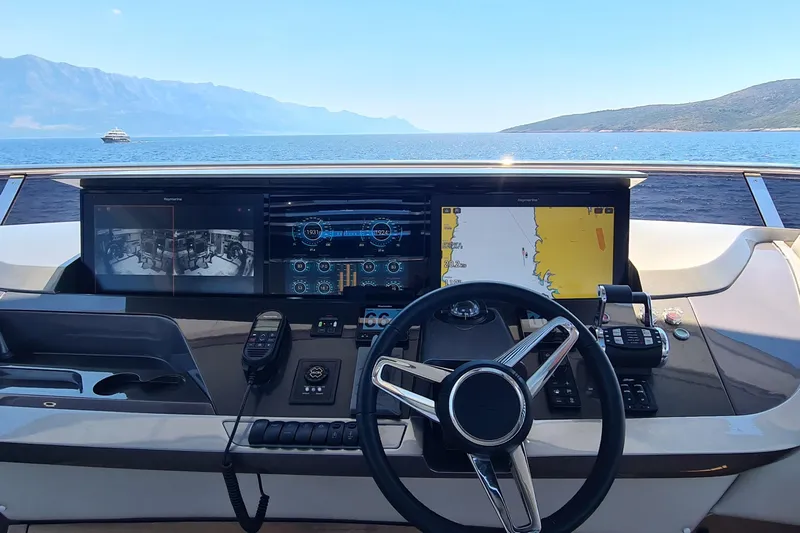  Yacht Photos Pics Helm of 2022 Princess Y85 yacht with navigation screens and steering wheel, overlooking serene ocean view.