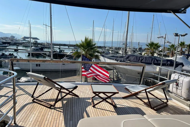  Yacht Photos Pics Luxurious 2022 Princess Y85 yacht deck with chairs, table, and marina view.