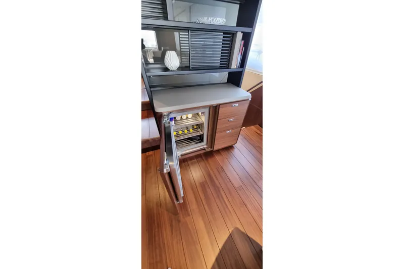  Yacht Photos Pics Luxurious interior of 2022 Princess Y85 yacht with open wine cooler and wooden flooring.