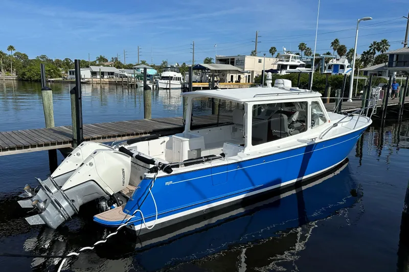 Tumalum Yacht Photos Pics 2023 MJM 35 boat docked, featuring a sleek blue and white design with twin Mercury engines.