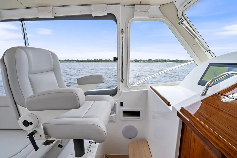 Tumalum Yacht Photos Pics Captain's chair and helm inside 2023 MJM 35 boat, overlooking serene water view.