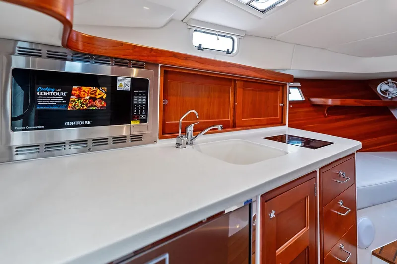 Tumalum Yacht Photos Pics Luxurious 2023 MJM 35 yacht kitchen with microwave, sink, and wooden cabinetry.