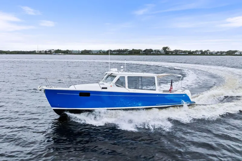 Tumalum Yacht Photos Pics 2023 MJM 35 boat cruising on open water with scenic shoreline background.