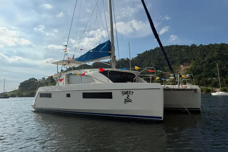 Sweet 2 Bad Yacht Photos Pics 2016 Leopard 404 catamaran with colorful flags, anchored in scenic bay.