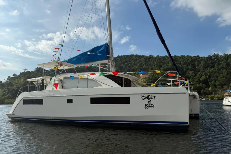 Sweet 2 Bad Yacht Photos Pics 2016 Leopard 404 catamaran with colorful flags, named "Sweet 2 Bad," on a scenic waterway.