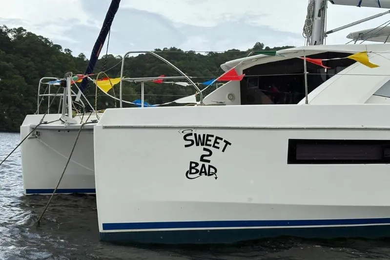 Sweet 2 Bad Yacht Photos Pics Catamaran "Sweet 2 Bad" on water, Leopard 404 model, 2016, with colorful flags.